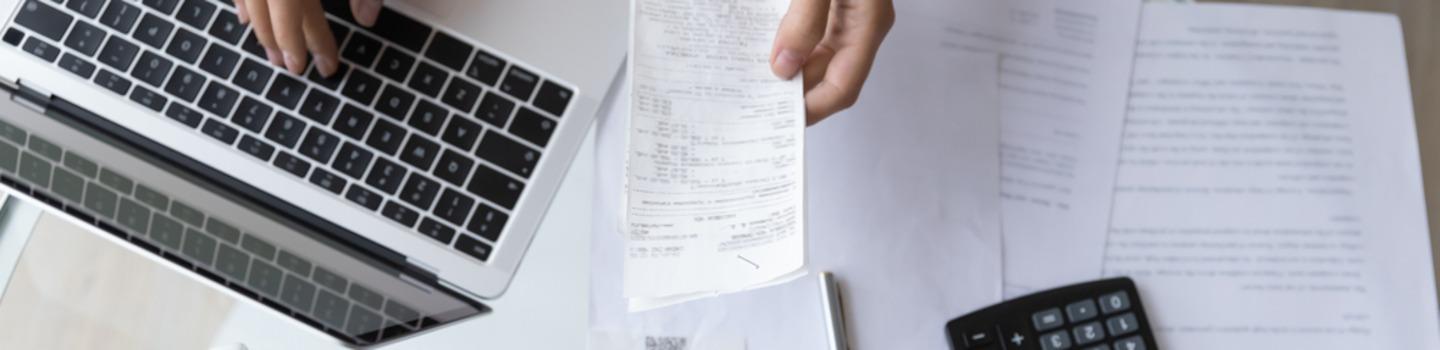Business owner calculating expenses with receipts, laptop and calculator