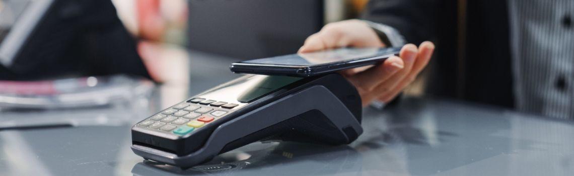 Customer paying at card machine with mobile phone